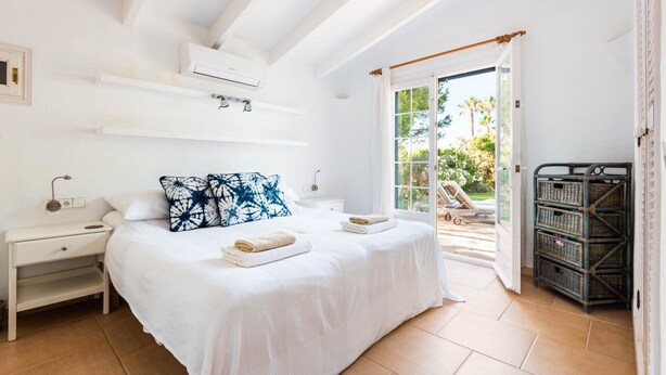 Un dormitorio con cama, mesitas de noche, aire acondicionado, una ventana y vistas al exterior.