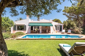 Ein Haus mit Swimmingpool, überdachter Terrasse und Garten.