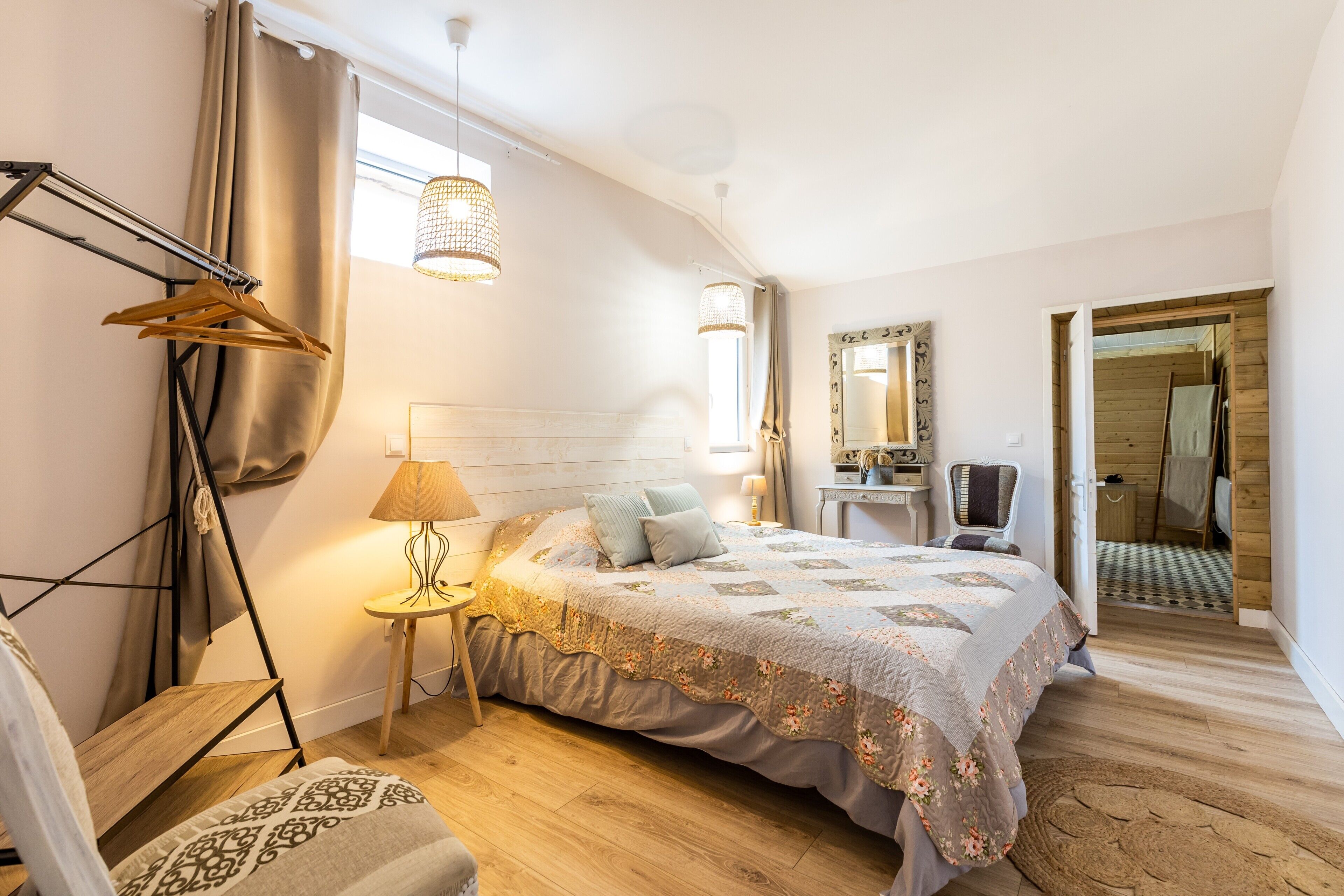 Une chambre à coucher comprenant un lit, une table de chevet, une lampe, un luminaire suspendu, un miroir et une armoire.