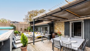 Un patio cubierto al aire libre con piscina, una mesa de comedor y una zona de estar.
