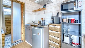 A compact kitchen with a refrigerator, microwave, and built-in oven.