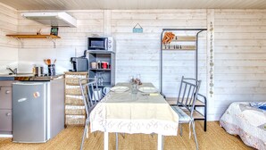 A compact kitchen with a refrigerator, microwave, and wooden shelves.