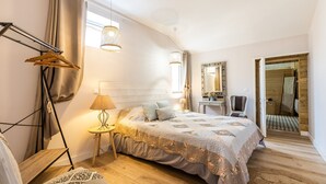Ein Schlafzimmer mit einem Bett, einem Nachttisch mit Lampe, einer Hängelampe, einem Spiegel und einem Kleiderschrank.