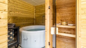 Eine Holzhütte mit Whirlpool, Dusche und Ablagefläche.