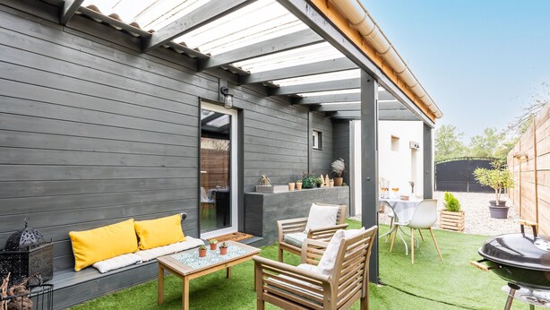 Eine Terrasse mit einer Holzbank, einem Tisch und einem Grill.