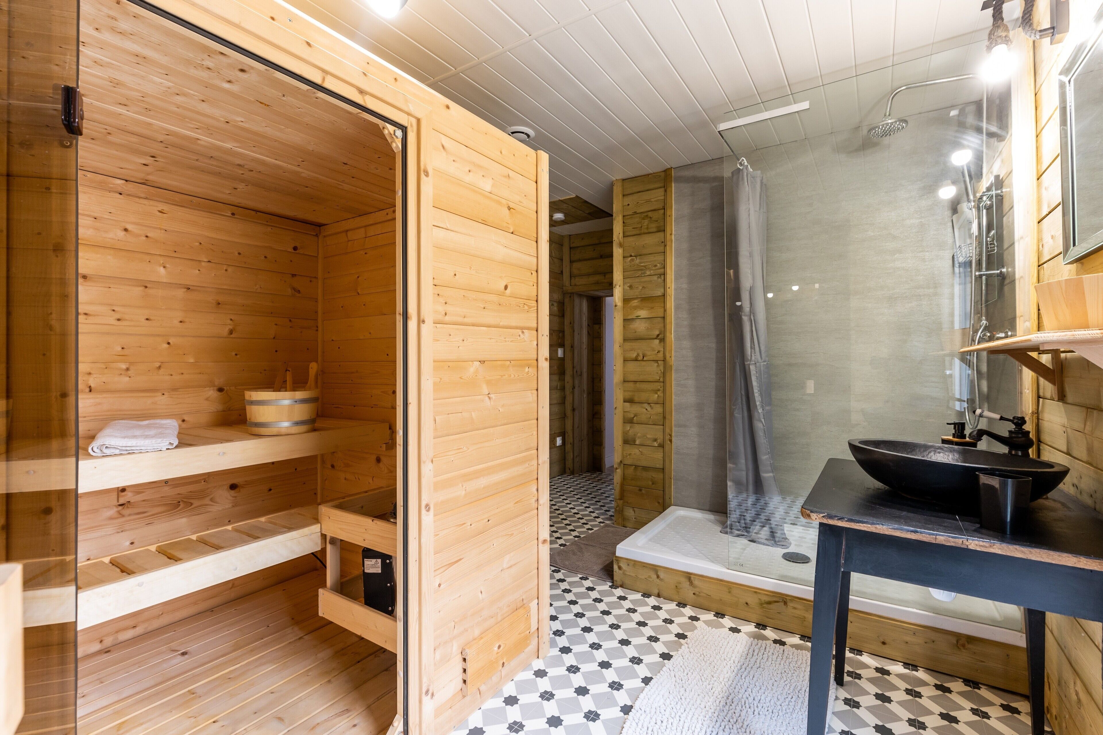 A wooden cabin interior with a sauna, a shower, and a sink.