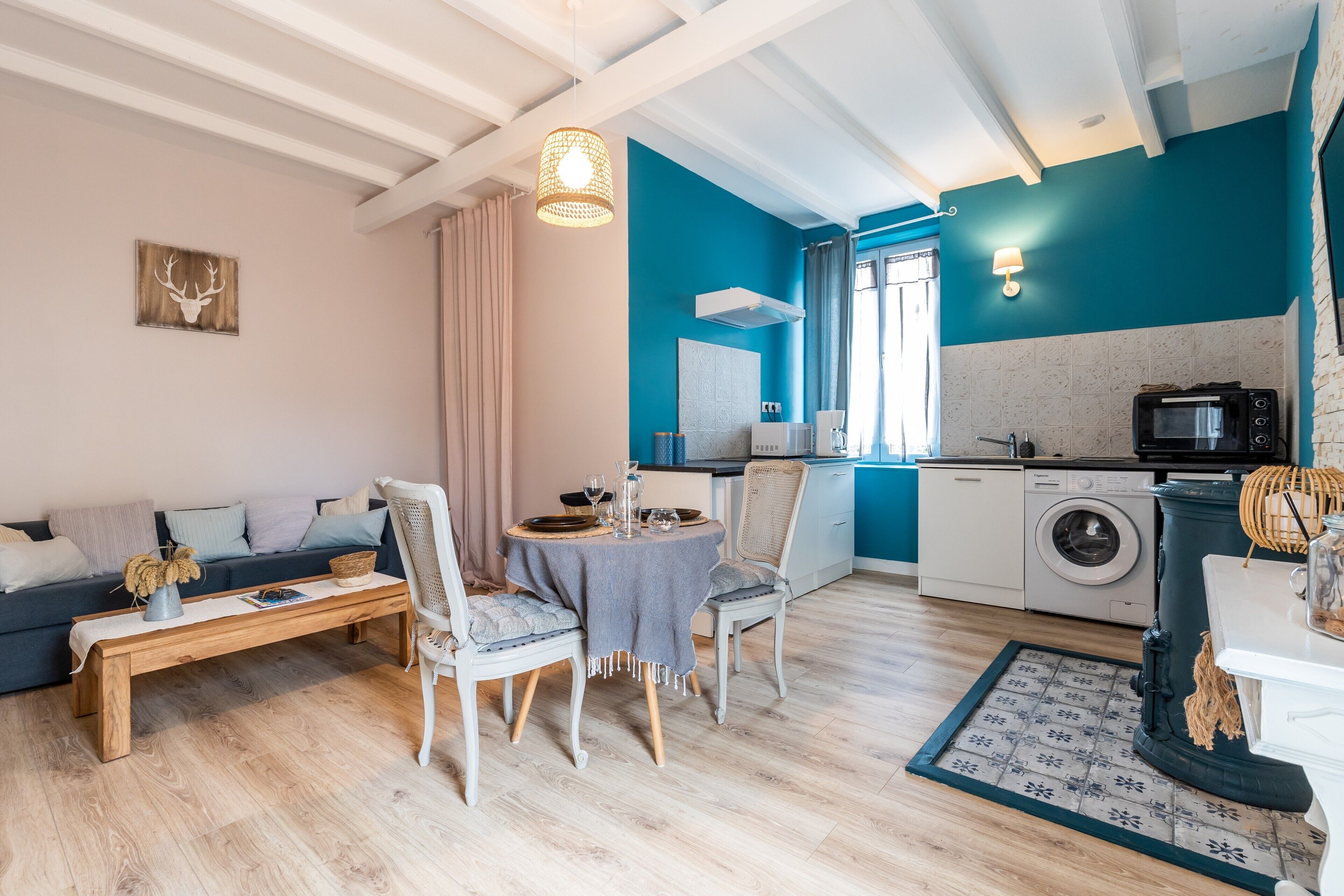 A modern living room with a sofa, dining table, chairs, a bench, and a kitchen area with appliances.