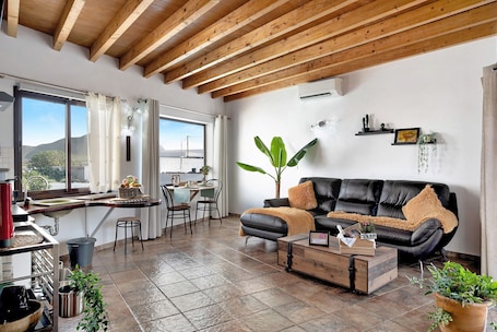 A modern living room with a black leather sofa, wooden coffee table, and potted plants.. Holiday Home 'Guenia I' with Mountain View, Wi-Fi and Air Conditioning