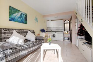 Un salon avec un canapé, une table basse et une cuisine en arrière-plan.