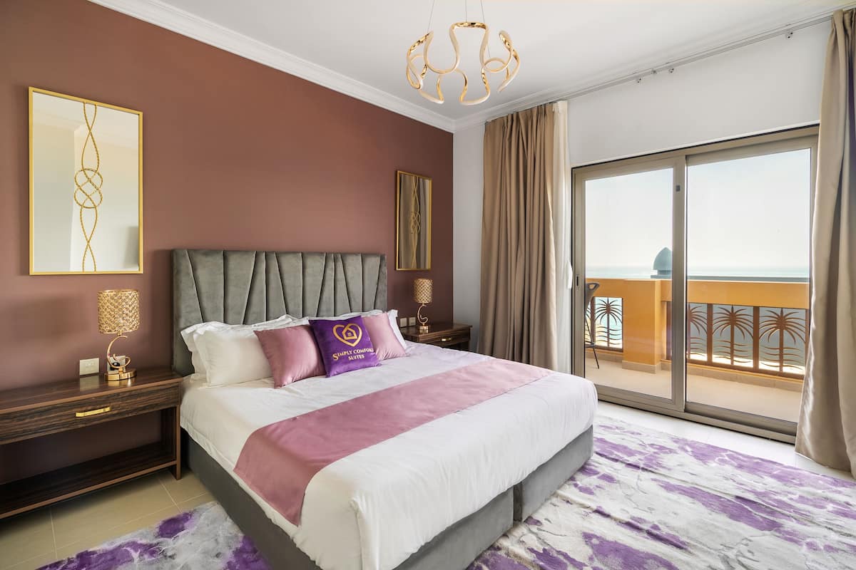 Een ruime slaapkamer met een groot bed, een balkon met uitzicht en modern interieur.