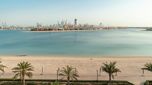 Ein Strand mit Palmen und einer Stadtkulisse im Hintergrund.