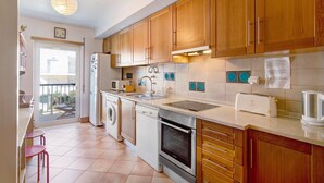 Una cocina con armarios de madera, lavavajillas, horno, fregadero y tostadora.