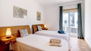 Habitación de hotel con dos camas, un balcón y vistas al exterior.