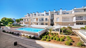 Un moderno complejo de apartamentos con piscina, balcones y un jardín ajardinado.