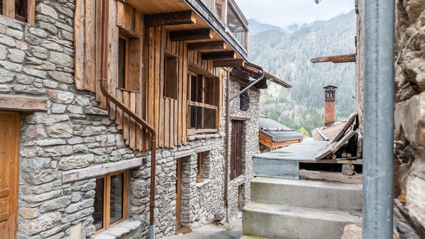 A stone building with wooden balconies and a staircase leading to a wooden deck.