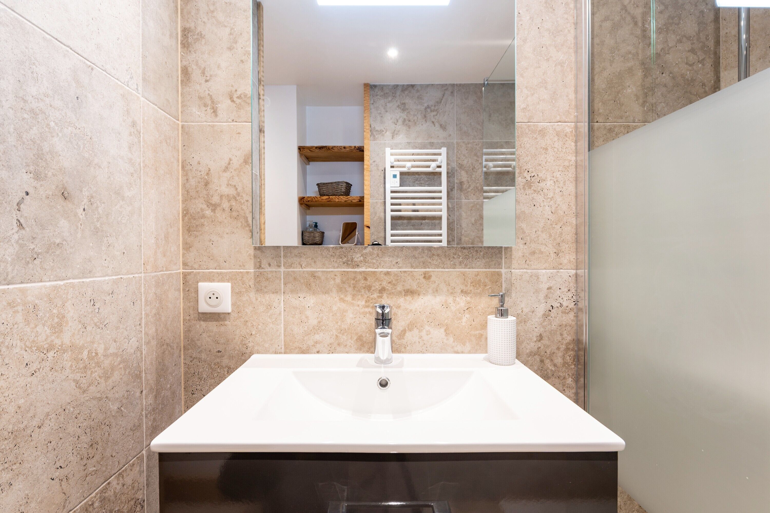 A bathroom with a white sink, a mirror, and a towel rack.