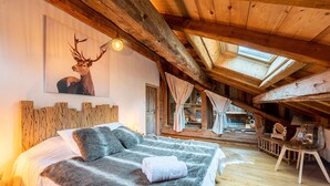 A bedroom with a large bed, wooden beams, a skylight, and a deer painting on the wall. - Chalet "Alouette" with Private Terrace, 2 Balconies & Wi-Fi (Champagny-en-Vanoise)