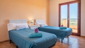 A hotel room with two beds, a nightstand, a lamp, and a sliding glass door to the outside. - Finca "Son Puca" with Mountain View, Pool & Wi-Fi (Petra)