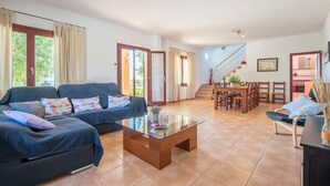 A spacious living area with a sofa set, a glass coffee table, and a dining area with wooden furniture. - Finca "Son Puca" with Mountain View, Pool & Wi-Fi (Petra)