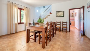 A dining area with a wooden table and chairs, a staircase, and a view of the outdoors. - Finca "Son Puca" with Mountain View, Pool & Wi-Fi (Petra)