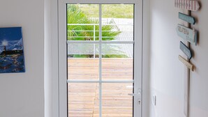 A door with a view of a wooden deck and a signpost with destination names.