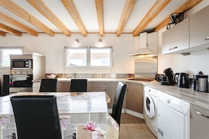 A modern kitchen with wooden beams, a washing machine, and a dining area with a table and chairs.