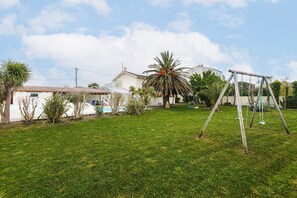 Un cortile residenziale con altalena, palma e casa con tetto in tegole.