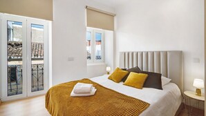 Ett hotellrum med en säng, ett fönster, en dörr och utsikt över omgivningen.