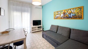 A living room with a sofa, a television on a stand, a dining table, and a painting on the wall. - Apartment "Casa Giovanna" with Private Terrace, Private Balcony & Wi-Fi (sanremo)