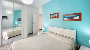 A bedroom with a bed, a nightstand, a lamp, a mirror, and two framed pictures on the wall. - Apartment "Casa Giovanna" with Private Terrace, Private Balcony & Wi-Fi (sanremo)