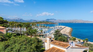 A coastal marina with boats, a rocky shoreline, and a mountainous backdrop. - Apartment "Sweet Sea" in Port of Alcudia with Shared Pool, Shared Terraces & Wi-Fi (Puerto de Alcudia)