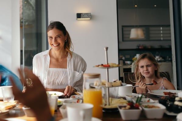 Un coin repas avec une table mise pour le petit-déjeuner, comprenant des assiettes, des tasses et une présentation de fruits.