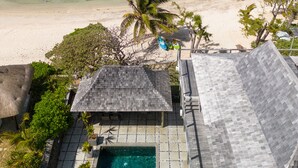 A beachfront property with a swimming pool, a view of the ocean, and a thatched-roof structure. - Koki Bonheur by muse villas (Poste Lafayette)