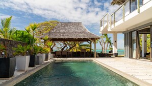 A swimming pool with a stone-lined edge, surrounded by potted plants and a gazebo. - Koki Bonheur by muse villas (Poste Lafayette)