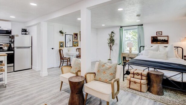 Una habitación moderna y luminosa con cama, zona de estar y cocina.