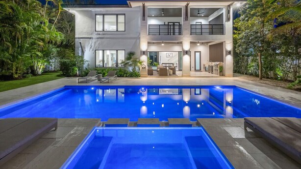 A modern two-story house with a swimming pool in front.