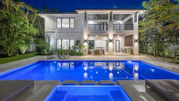 Une maison moderne à deux étages avec une piscine à l’avant.