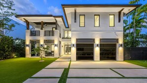 A modern two-story house with a covered patio, a garage, and a well-maintained lawn.