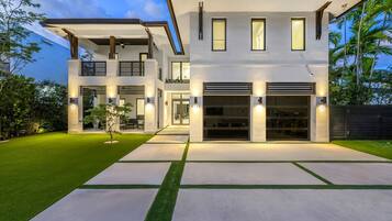Une maison moderne à deux étages, dotée d’un patio couvert, d’un garage et d’une pelouse bien entretenue.