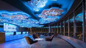 Un intérieur moderne avec des motifs géométriques au plafond et un espace bar doté de sièges.
