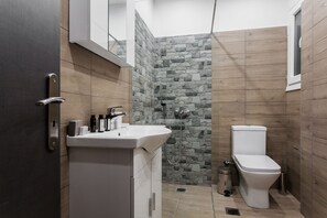 Une salle de bain moderne avec un mur en pierre, un lavabo blanc et des toilettes.
