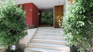 A staircase leading to a building entrance, flanked by large potted plants. - Gorgeous 1BR Apartment in Kolonaki (Athens)