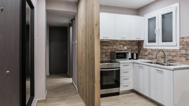 A modern kitchen with white cabinets, a built-in oven, a microwave, and a sink. - Gorgeous 1BR Apartment in Kolonaki (Athens)