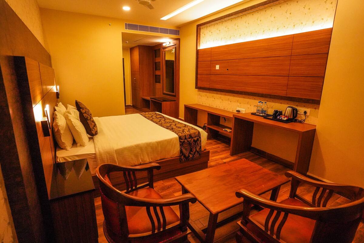 Une chambre d’hôtel avec un lit, des meubles en bois, un bureau et un grand miroir.