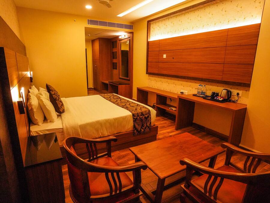 Una habitación de hotel con una cama, muebles de madera, un escritorio y un espejo grande.
