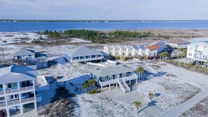 Une propriété située en bord de mer, comprenant plusieurs bâtiments, notamment une grande maison dotée d’un balcon et une plus petite maison avec une véranda.