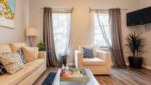 Una sala de estar con dos sofás, una mesa de centro, un televisor y una planta en maceta.
