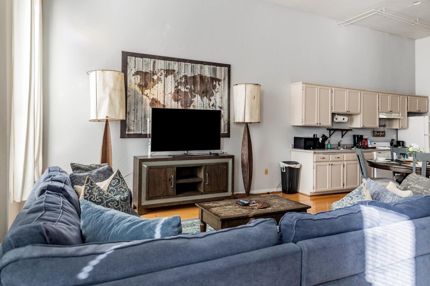 A living room with a sofa, a coffee table, a TV, and a world map artwork.