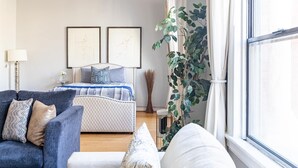 A bedroom with a bed, a blue sofa, and a large window. - Spacious 1 BR 700 sq ft loft suite with free parking, steps to the Convention Center and Gaslamp dining.  Ideal for business or group travel. (San Diego)