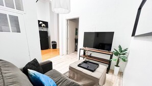 Una sala de estar moderna con un sofá, una mesa de centro y un televisor sobre un mueble.